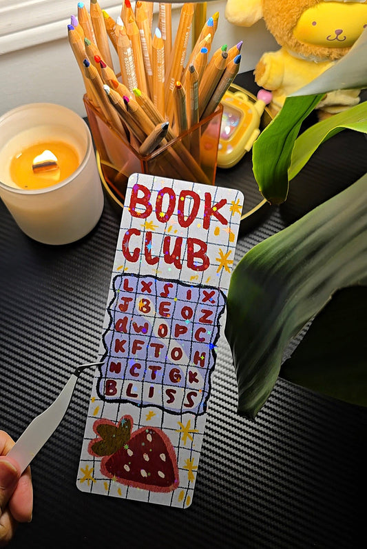Book Club Word Search holographic bookmark flat lay showing word search grid with BLISS hidden word and strawberry illustration