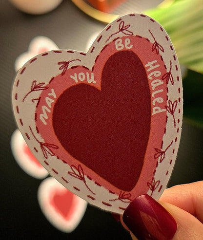 Heart-shaped card with text held by a hand against a blurred background