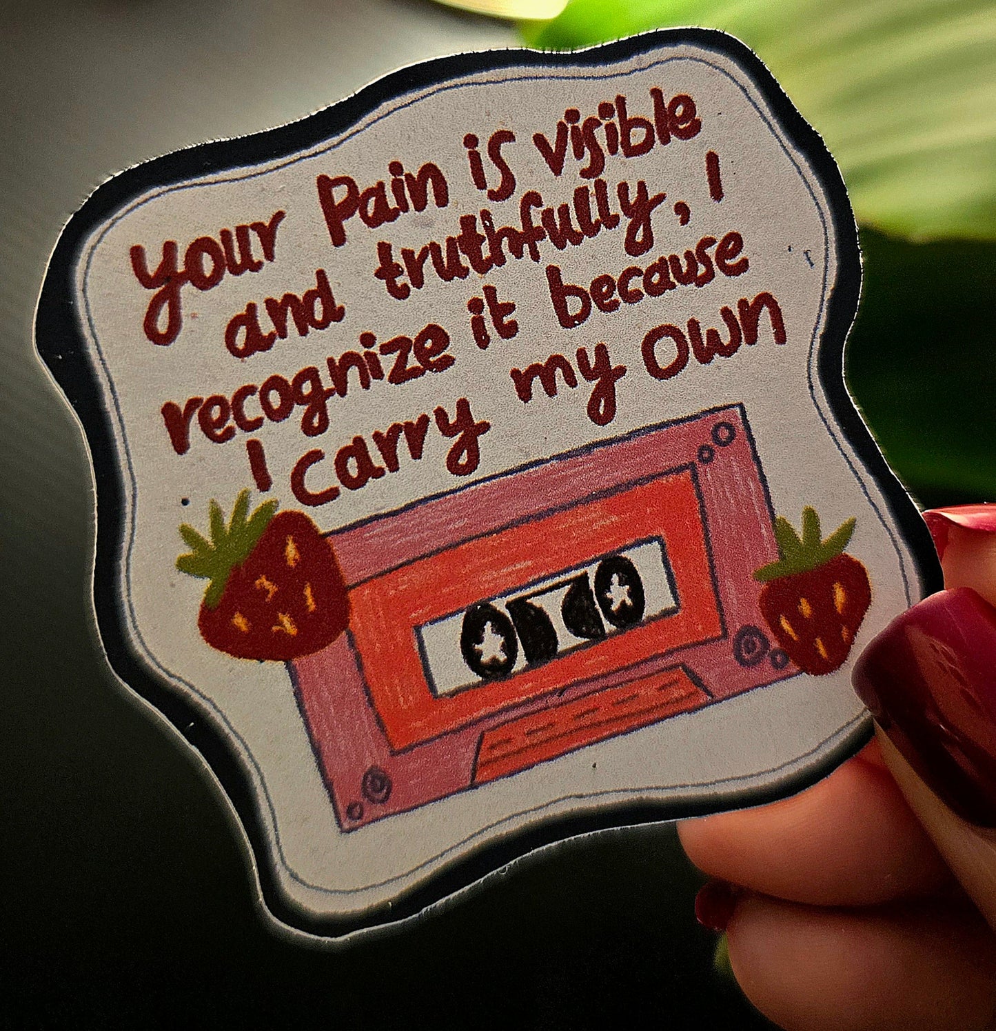 Sticker with a cassette tape design and text held by a hand