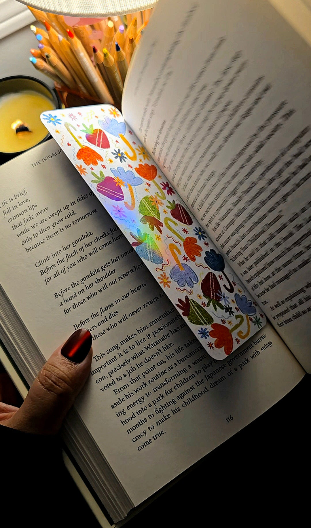 Strawberry Umbrella holographic bookmark in use inside a book showing full rainbow holographic shine with strawberry and umbrella design