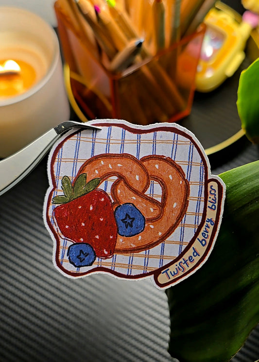Twisted Berry Bliss die-cut sticker featuring a pretzel heart with strawberry and blueberries on a plaid background